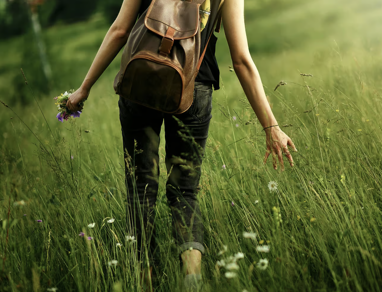 An adult person walks through high grass.