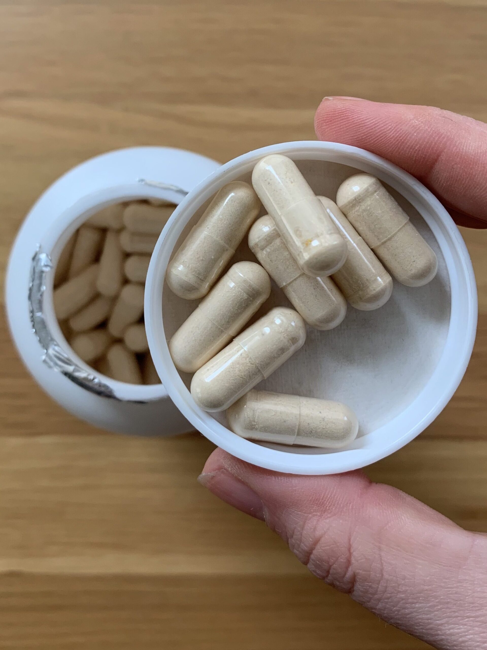 A hand holding a cap full of Seeking Health prenatal vitamins.