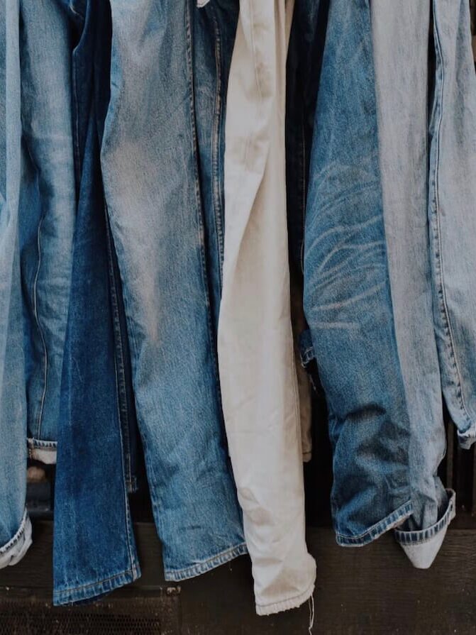 A row of denim jeans in various shades of blue hangs side by side.