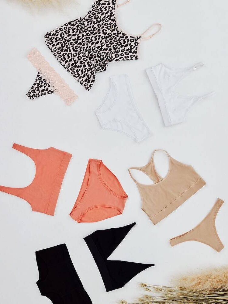 A selection of women's lingerie laid out on a white surface, including bras, panties, and a camisole in various colors and patterns.