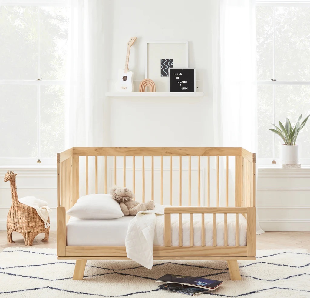 A toddler bed with rail in a nursery.