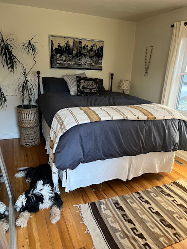 Bedroom with a wooden bed frame, a side table with a lamp, and a wall art piece. 