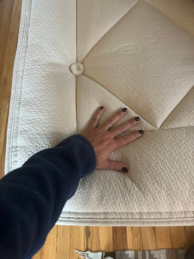 A hand pressing down on an Avocado mattress. 