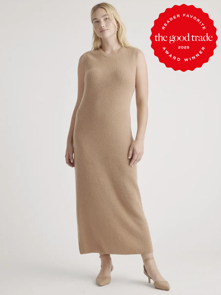 Person wearing a sleeveless, long beige knit dress and beige heels stands against a plain background.