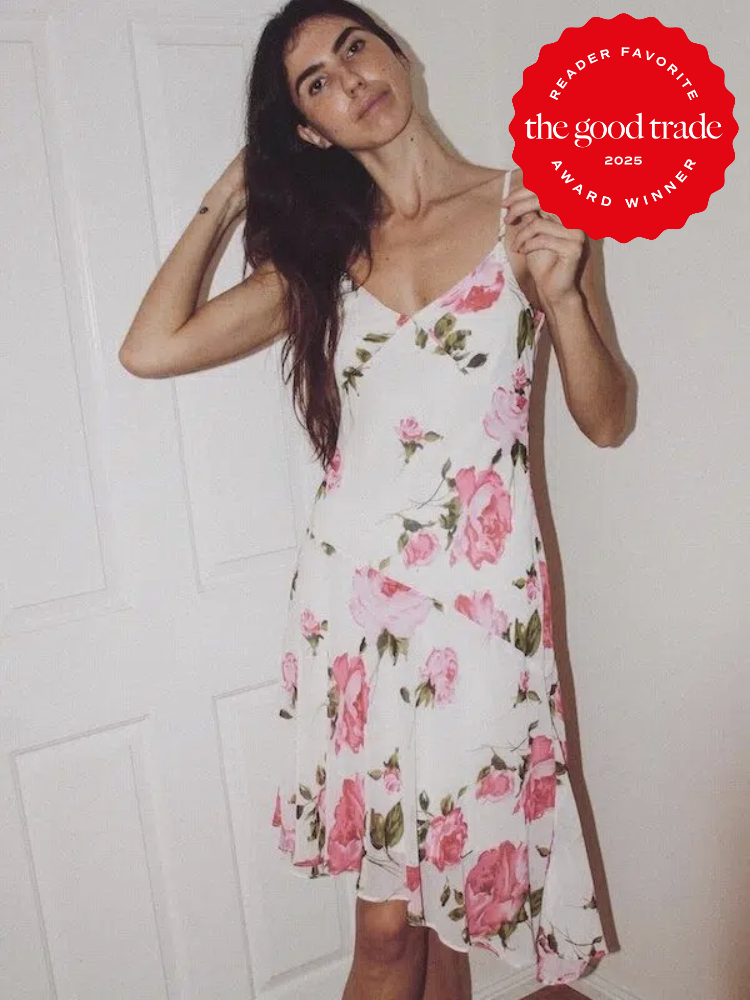 Person posing in a floral dress in front of a white door. There is a red award badge overlay that says "Reader Favorite, FashionGroomSpot, Award Winner 2025.