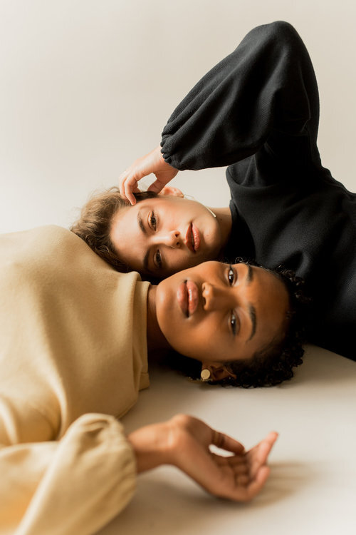Two women lay parallel, looking directly at the camera.
