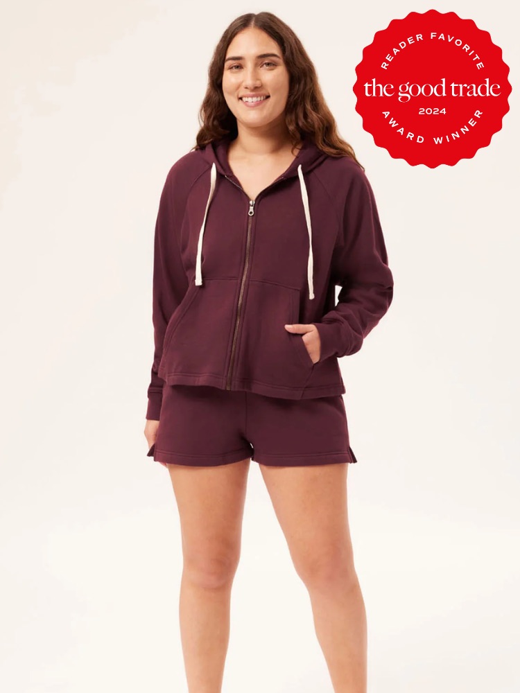 Person wearing a matching burgundy hoodie and shorts set, smiling, with a red award badge in the top-right corner reading "FashionGroomSpot 2024 Reader Favorite Award Winner.