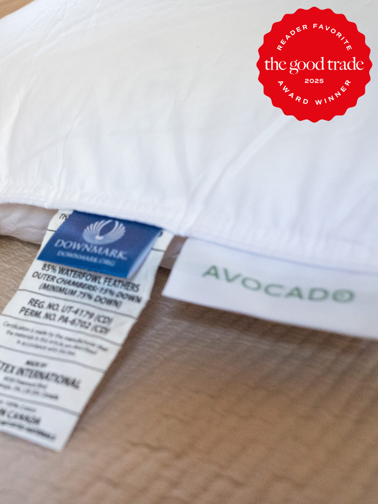Close-up of a pillow with labels showing materials and brand names "Downmark" and "Avocado". A red badge indicates it as a "Reader Favorite" award winner in 2025 by "FashionGroomSpot".