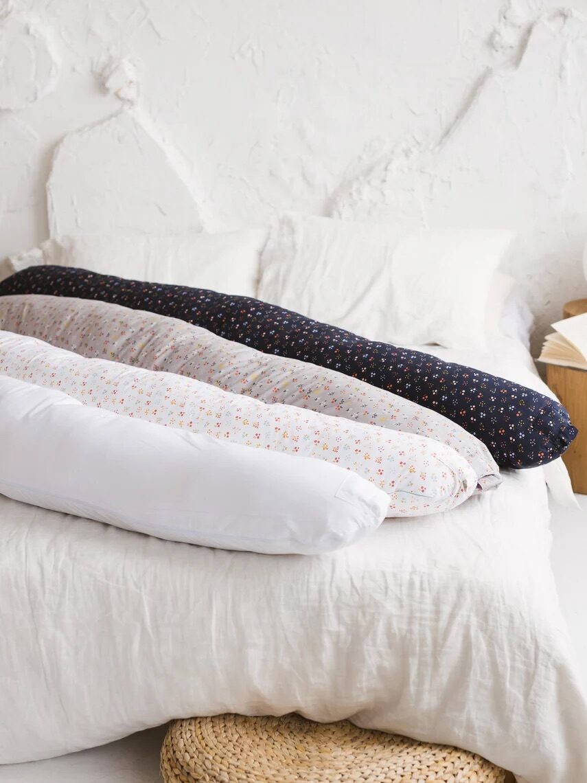 Four MINICAMP body pillows on a bed.