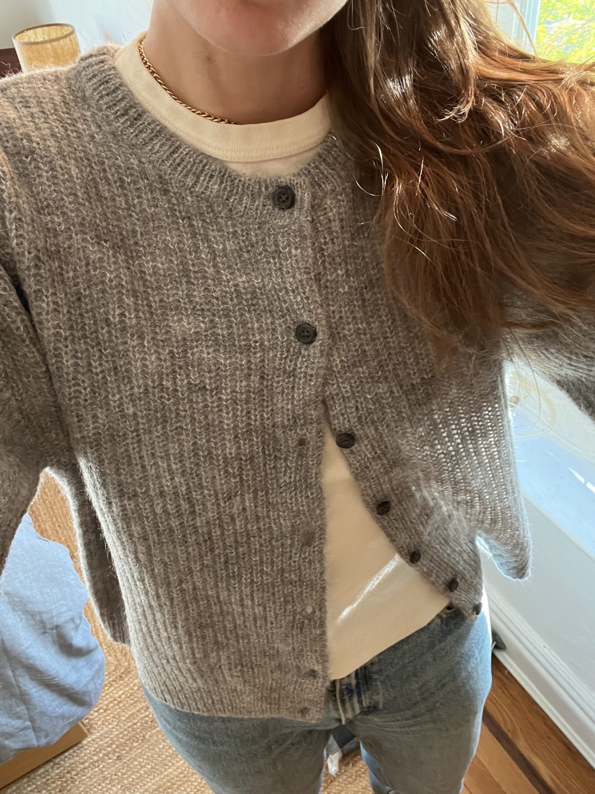 Close up of a TGT editor wearing a grey button down cardigan sweater from Jenni Kayne.