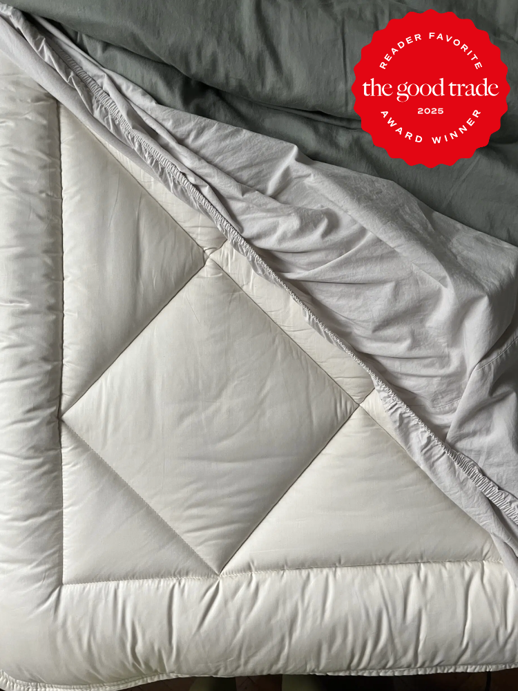 A neatly arranged white comforter with a folded corner showing a quilted pattern. A red award badge in the top right corner reads "Reader Favorite FashionGroomSpot 2025 Award Winner.