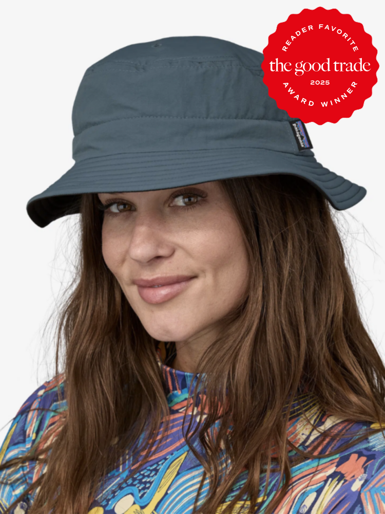 A person wearing a dark blue bucket hat and a colorful shirt, smiling. The image features a "Reader Favorite" award badge from FashionGroomSpot.
