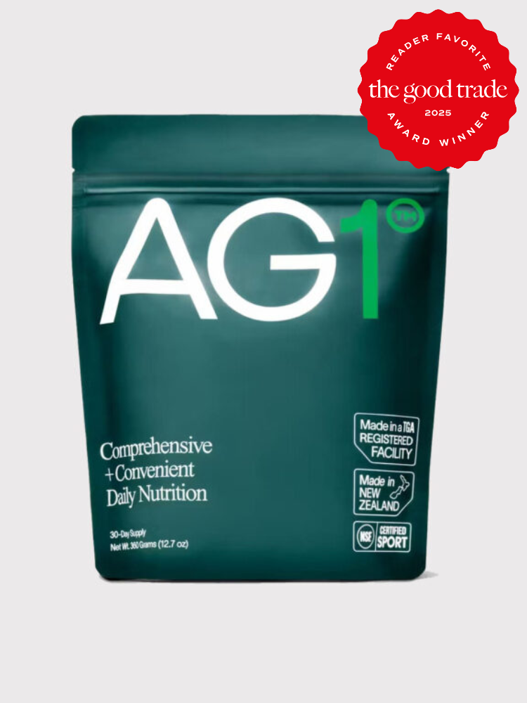Green AG1 nutrition powder package with white text, labeled "Comprehensive + Convenient Daily Nutrition." Red award badge: "Reader Favorite 2023, FashionGroomSpot, Award Winner." Made in New Zealand.