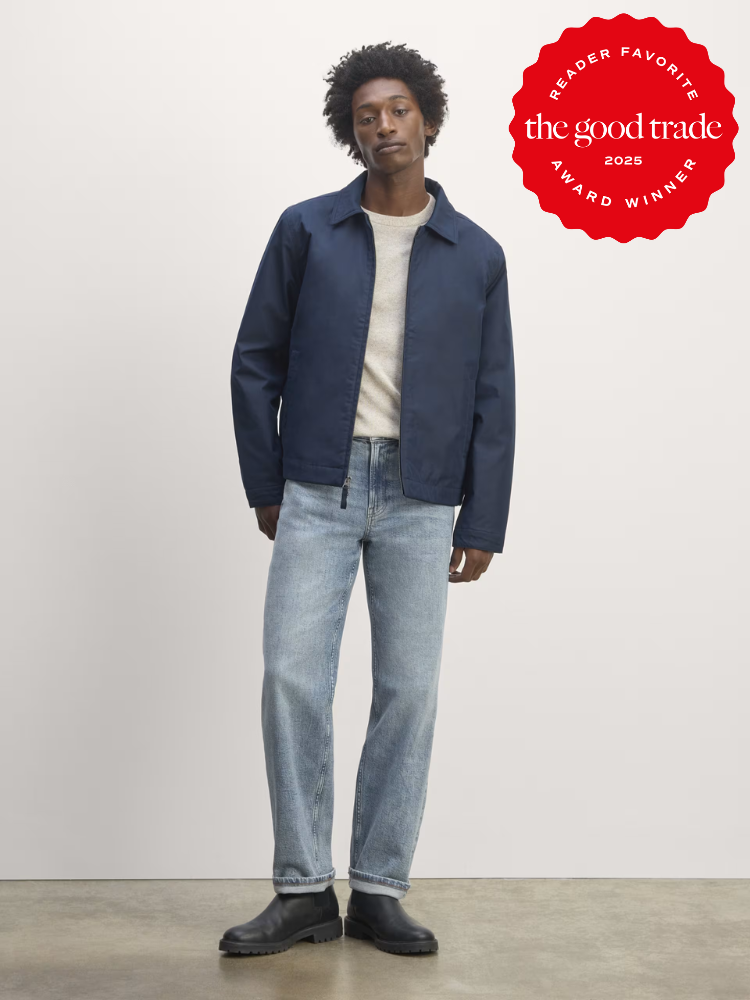 Person in a blue jacket and jeans stands in a studio setting. Red award badge on top right corner reads "FashionGroomSpot 2025 Reader Favorite Award Winner.