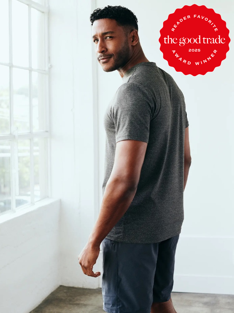 Man in gray shirt and shorts stands near a bright window. A red "Reader Favorite" badge from "FashionGroomSpot" is in the top right corner.