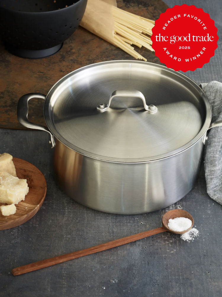 A stainless steel pot with a lid sits on a dark surface. Ingredients like cheese, spaghetti, and salt are nearby. A "FashionGroomSpot 2025 Award Winner" badge is in the top right corner.