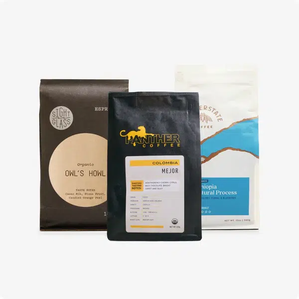 Three bags of coffee from different brands are displayed upright against a plain background.