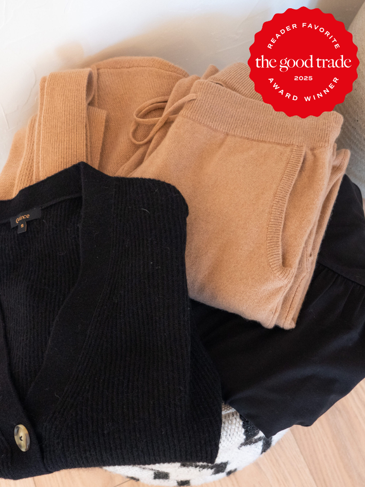 Folded black and beige clothing, including a black cardigan and beige pants, with an award-winning label from "FashionGroomSpot" indicating reader favorite for 2025.