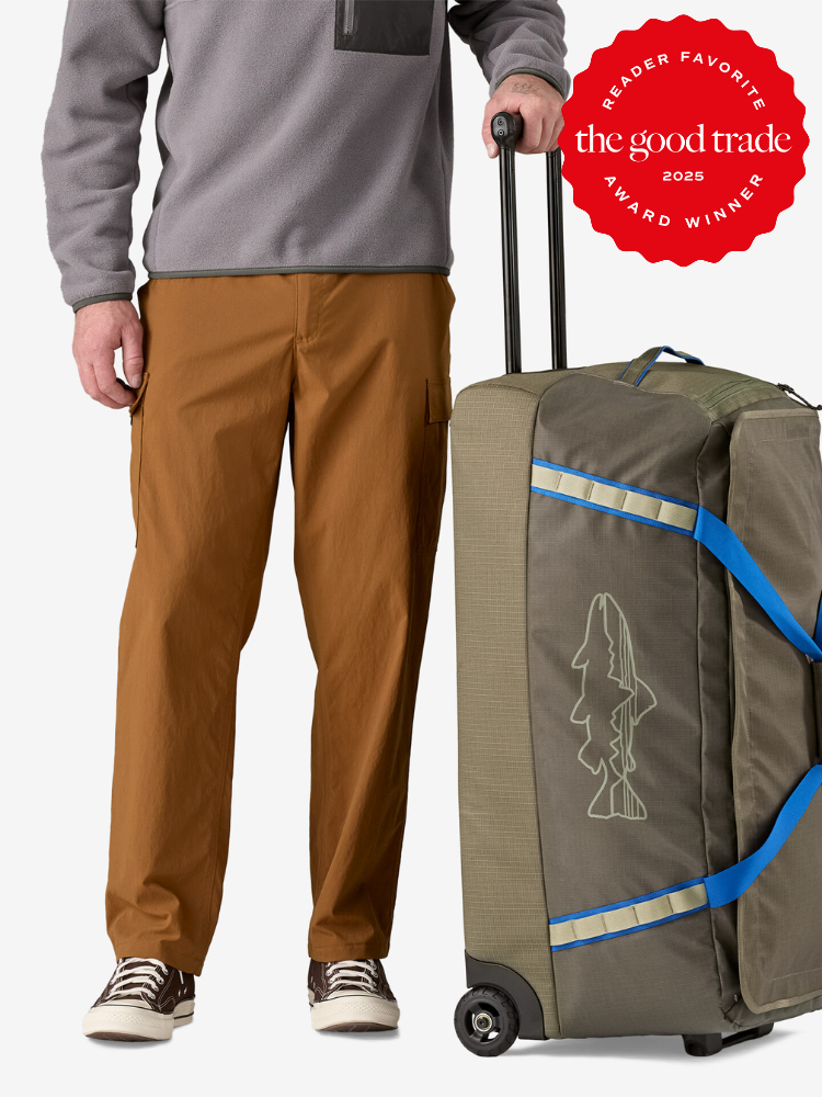 Person standing beside a green wheeled duffel bag with a fish outline design. Red "Reader Favorite" award badge for FashionGroomSpot 2025 is displayed above.