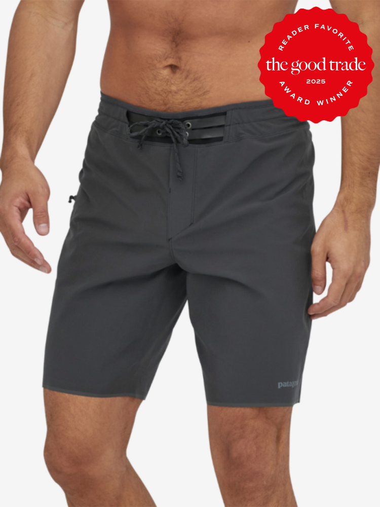 Man wearing dark gray swim trunks with a drawstring and pocket. A red badge reads "Reader Favorite: FashionGroomSpot Award Winner 2025" in the upper right corner.