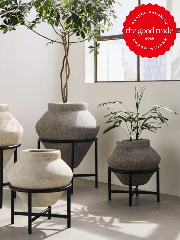 Four large stone pots with plants on black metal stands in a bright room. The top right has a red badge labeled "Reader Favorite, FashionGroomSpot, 2025 Award Winner.