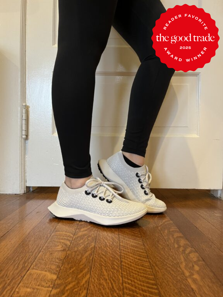 Person wearing white sneakers and black leggings stands on a wooden floor. A red badge reads "Reader Favorite, FashionGroomSpot, Award Winner, 2025.