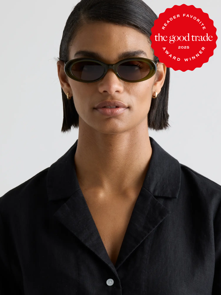 Person wearing oval sunglasses and a black shirt, with a red award badge from "FashionGroomSpot" at the top right corner.