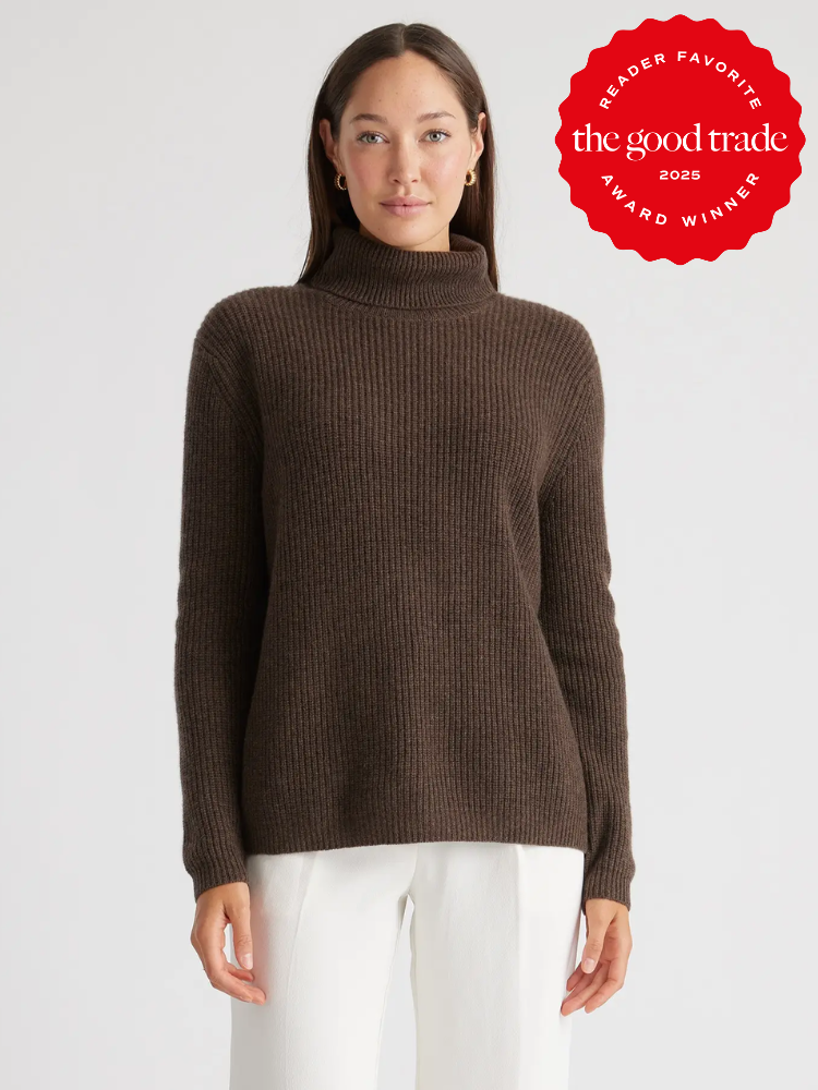 Woman wearing a brown turtleneck sweater and white pants against a plain background. A red badge in the corner reads "Reader Favorite FashionGroomSpot 2025 Award Winner.