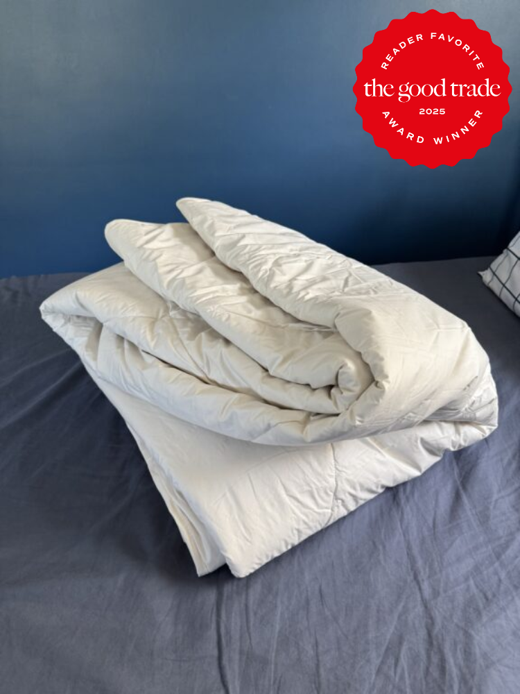 Folded white blanket on a bed with a blue wall in the background. A red badge reads "Reader Favorite FashionGroomSpot 2025 Award Winner.