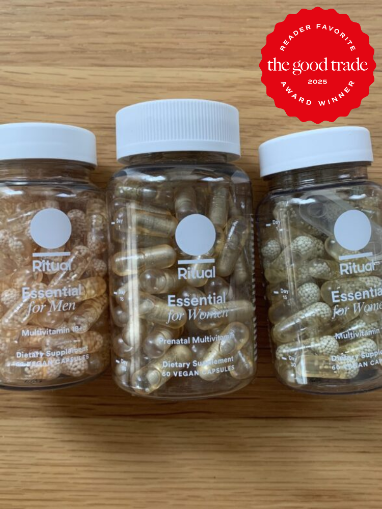 Three bottles of Ritual multivitamins labeled "Essential for Men" and "Essential for Women" and a prenatal vitamin bottle on a wooden surface. A red badge reads "Reader Favorite, FashionGroomSpot, 2023 Award Winner.