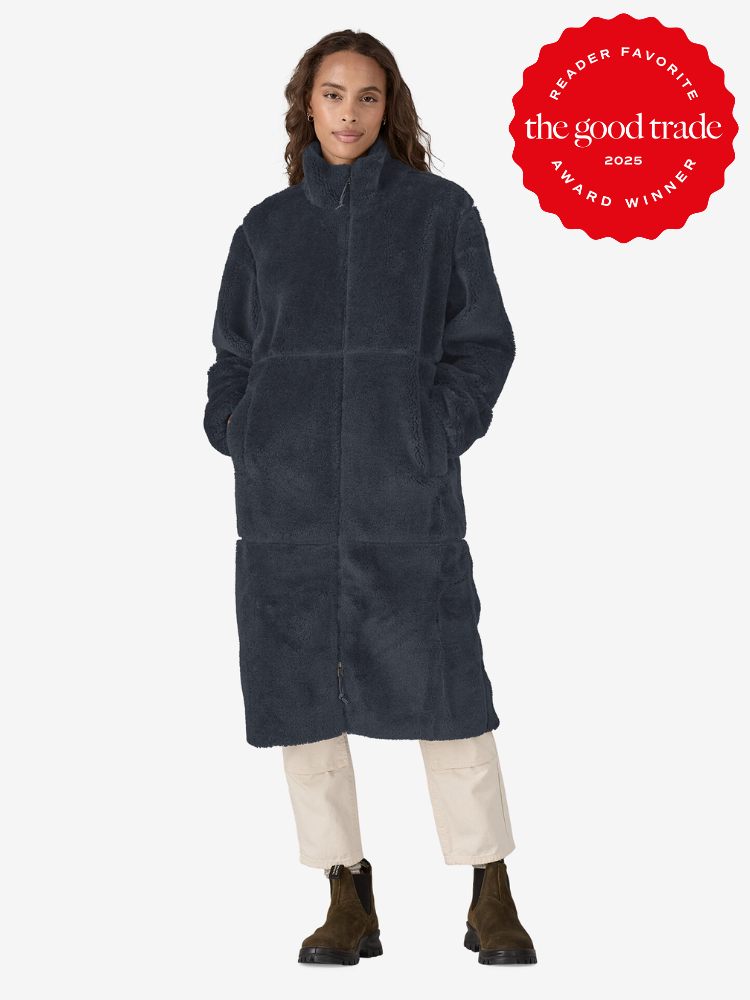 Person in a long, dark blue fuzzy coat with hands in pockets, light pants, and brown boots. A red "FashionGroomSpot 2025 Reader Favorite Award Winner" badge is displayed.