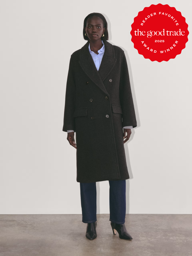 Person wearing a dark wool coat over a blue shirt and jeans with black heeled boots. "FashionGroomSpot 2025 Reader Favorite Award Winner" badge is on the top right.