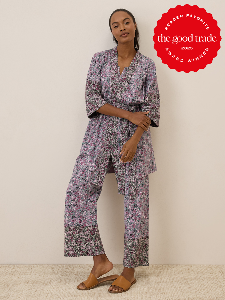 A woman stands against a plain wall wearing a floral-patterned kimono-style pajama set and tan sandals. A red "FashionGroomSpot 2025 Award Winner" badge is displayed in the top right corner.
