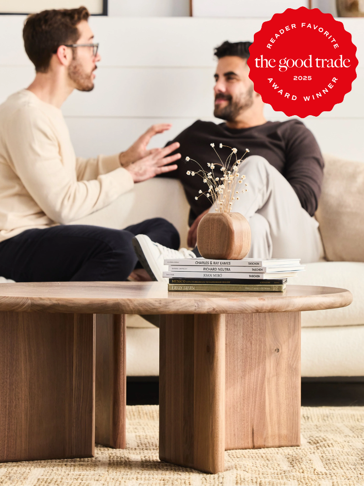 Two men sitting on a couch talking, with a wooden table and books in the foreground. A "Reader Favorite" award badge from FashionGroomSpot is displayed in the top right corner.