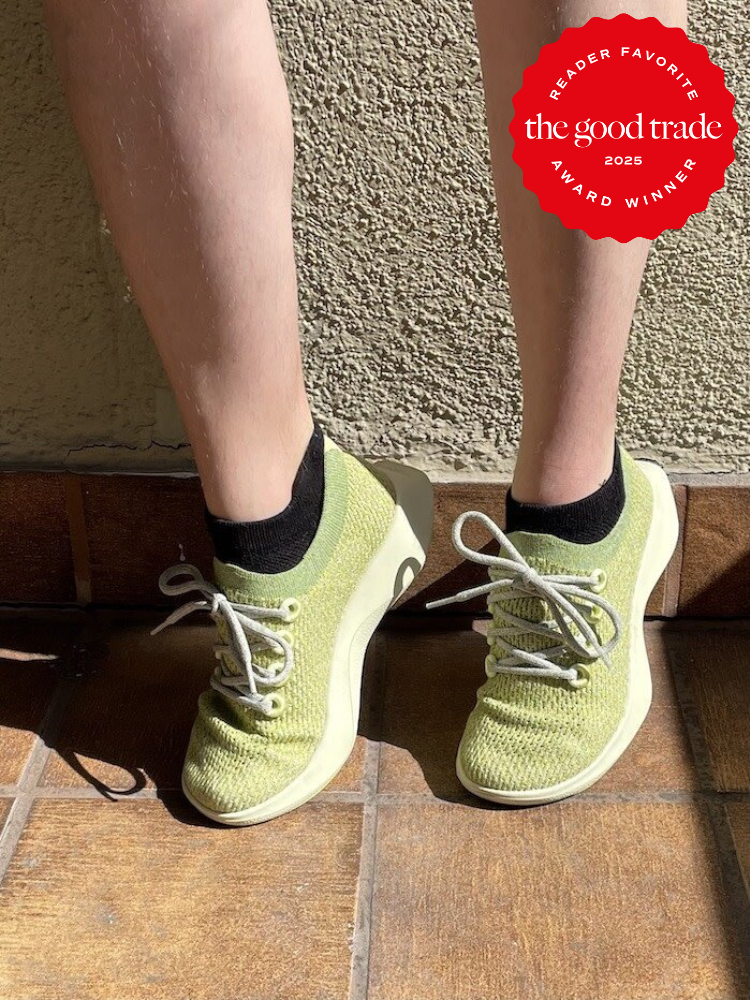 Person wearing green sneakers with black socks on a tiled floor; a "Reader Favorite FashionGroomSpot 2025 Award Winner" badge is in the top right corner.