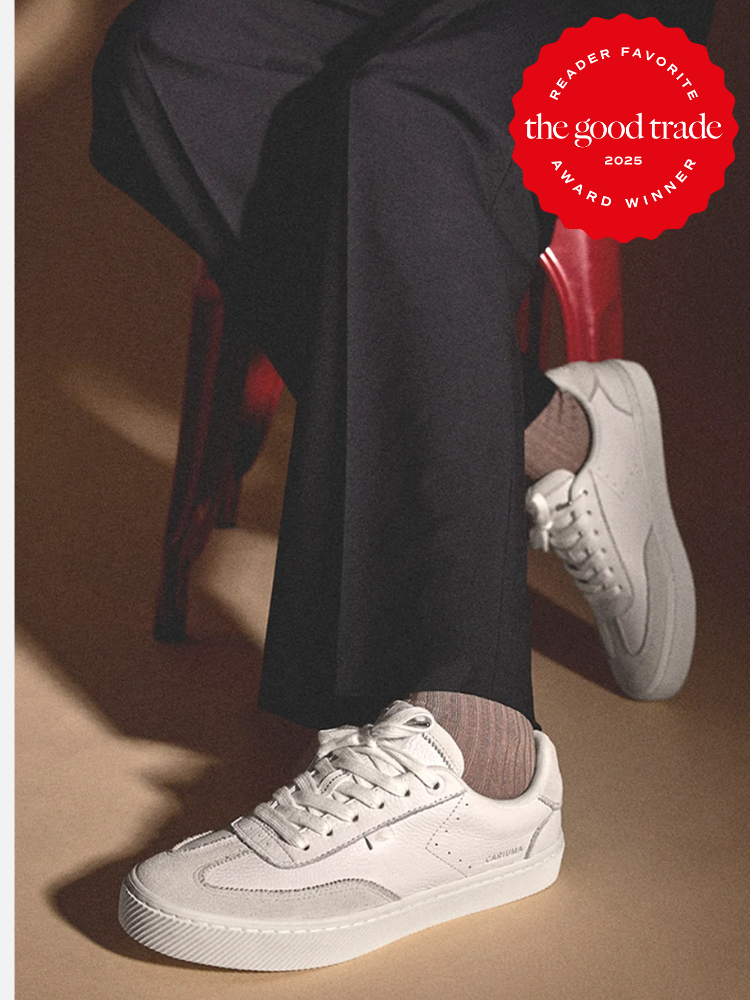 Person in dark pants seated on a red chair, wearing white sneakers and striped socks. A red badge in the top right corner reads "Reader Favorite FashionGroomSpot 2025 Award Winner.