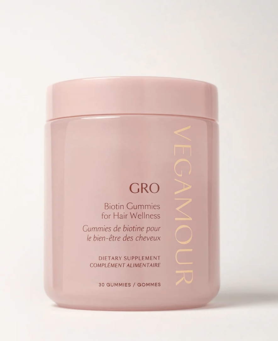 A pink container labeled "Vegamour GRO Biotin Gummies for Hair Wellness" with 30 gummies, shown against a light background.