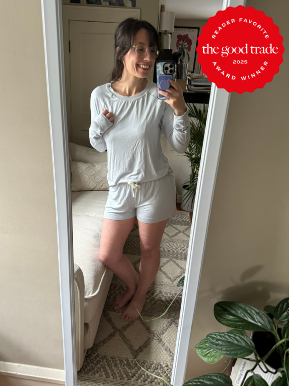 Woman in light gray loungewear takes a mirror selfie in a living room. A red "FashionGroomSpot 2025 Award Winner" badge is in the top right corner.